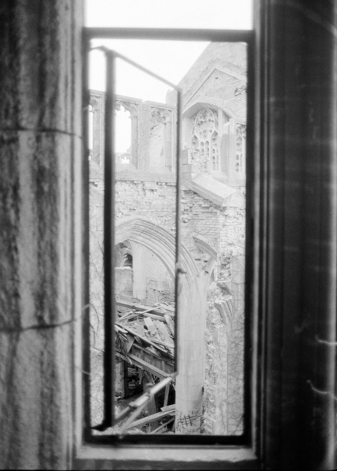 A black-and-white photo of the view through an abandoned church window.